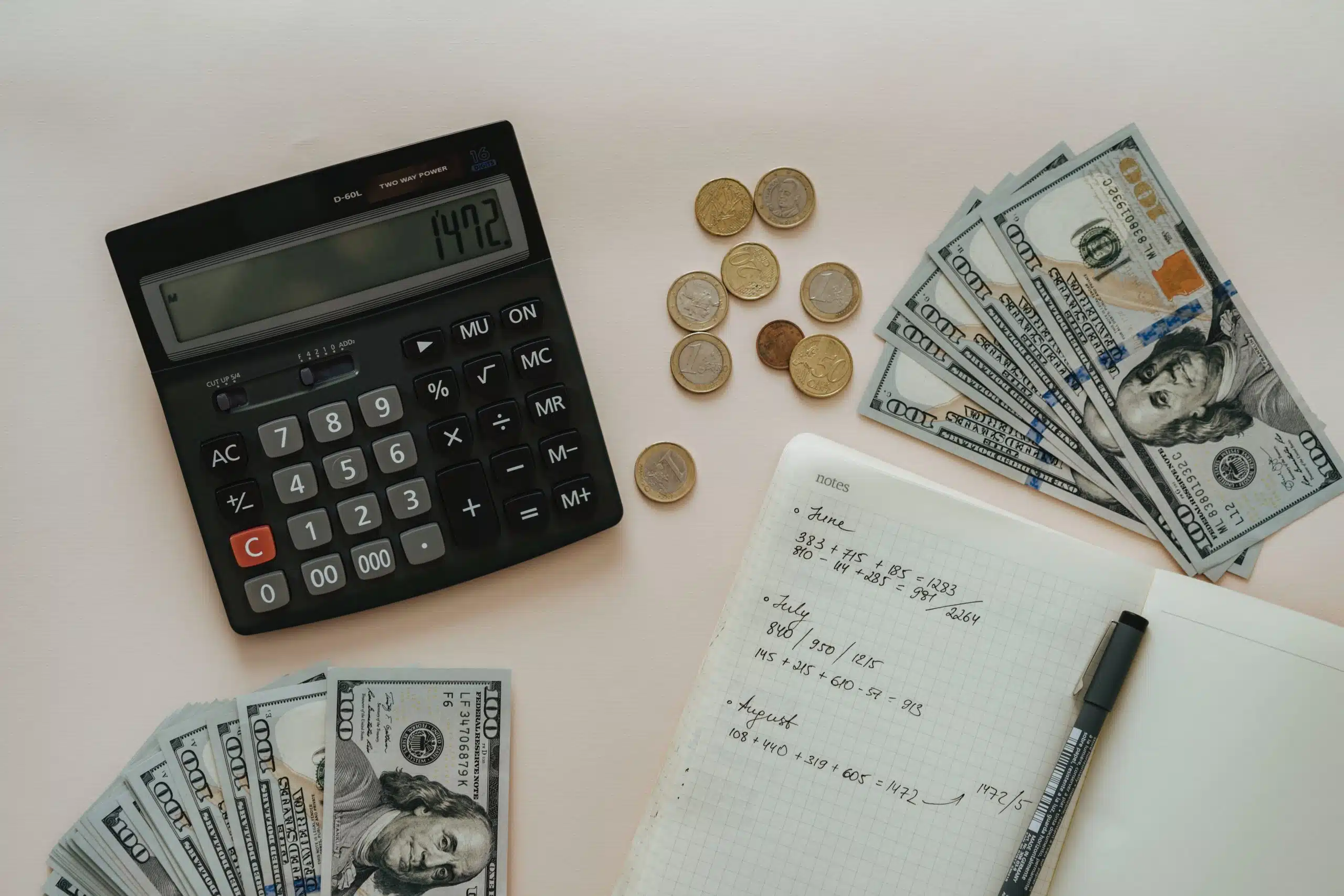 calculator, dollar bills, coins, notebook and a pen