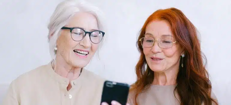 Two women lookign at a phone and smilingi