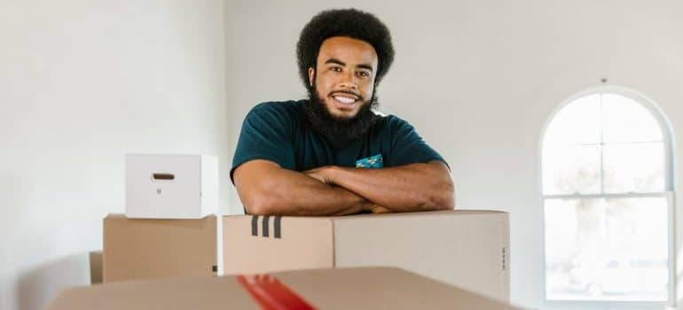 A man resting on the boxes and smiling.