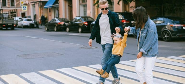 Parents crossing the street playfully with their child 