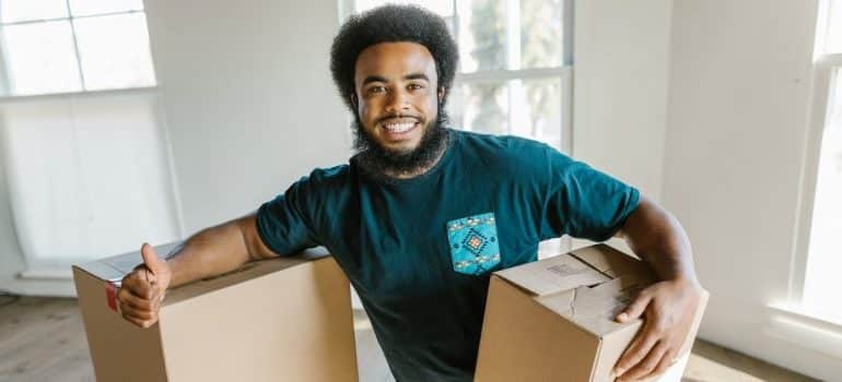 A man holding moving boxes and smiling. 