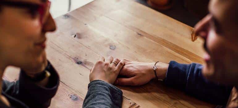 A couple sitting at a table and holding hands