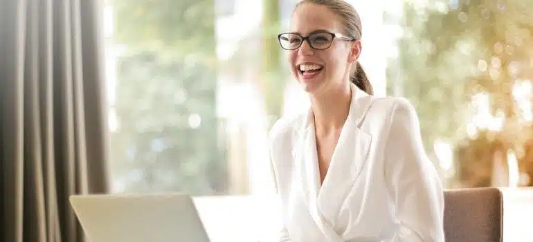 A woman doing work on her computer, smiling and searching for best NH places for young professionals