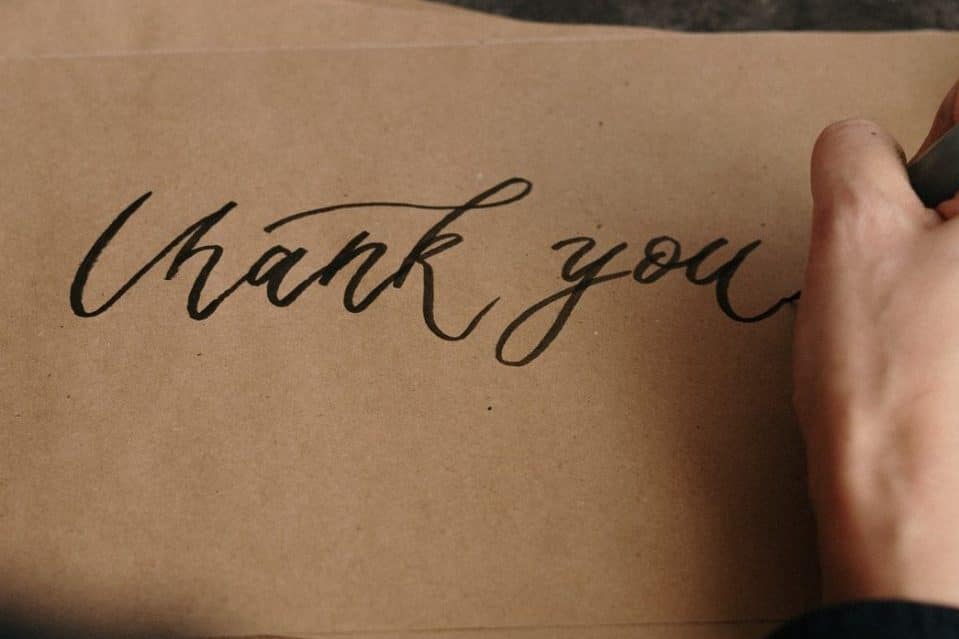 someone writing a thank you note on a piece of paper