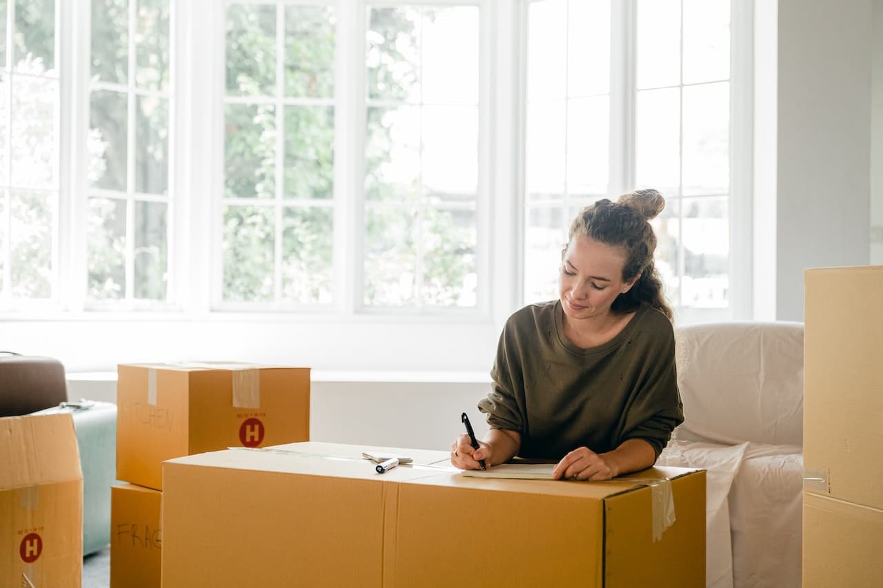 A woman making some plans and writing something on a moving box.